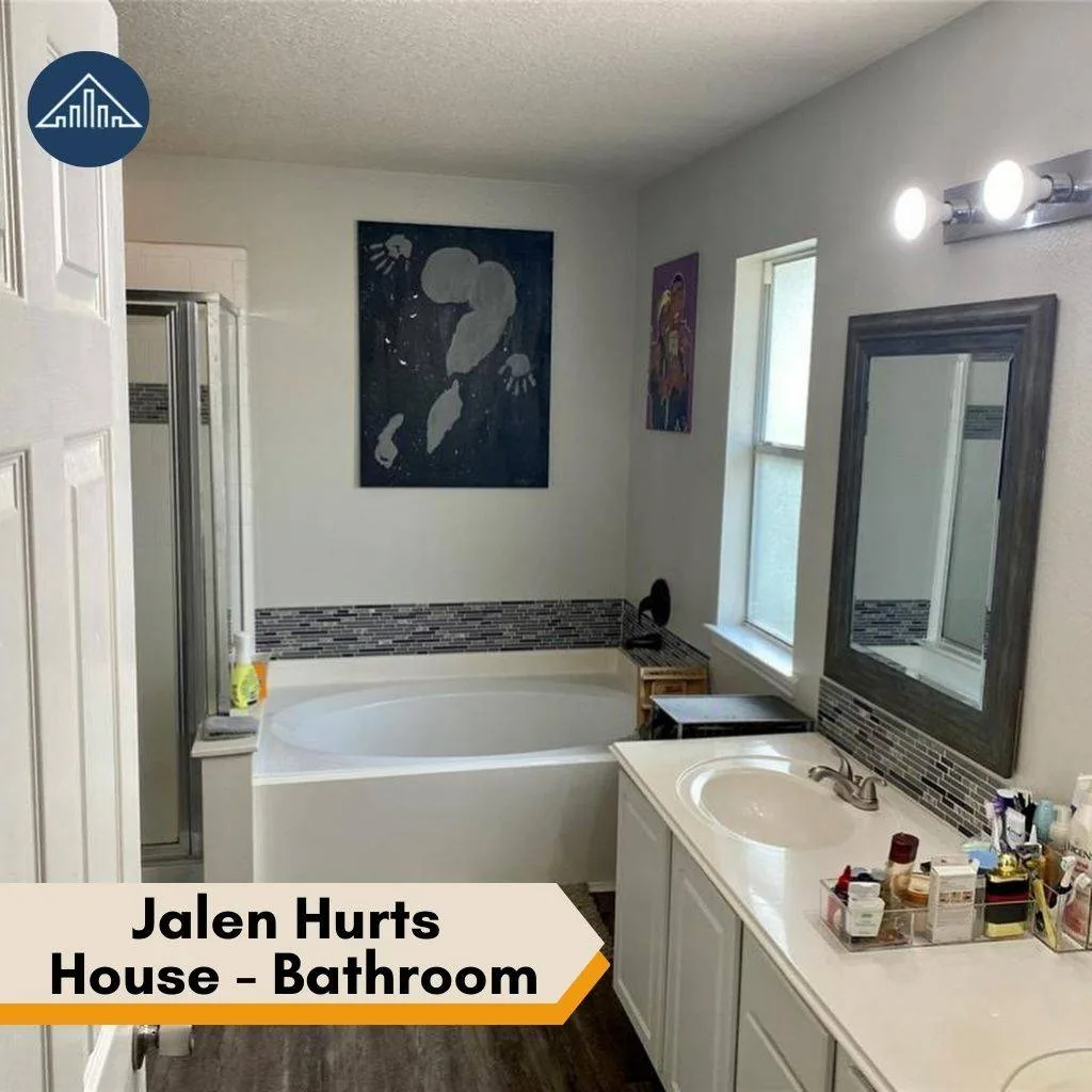 A white bathtub and tiled vanity setup are located in a bathroom in Jalen Hurts house.