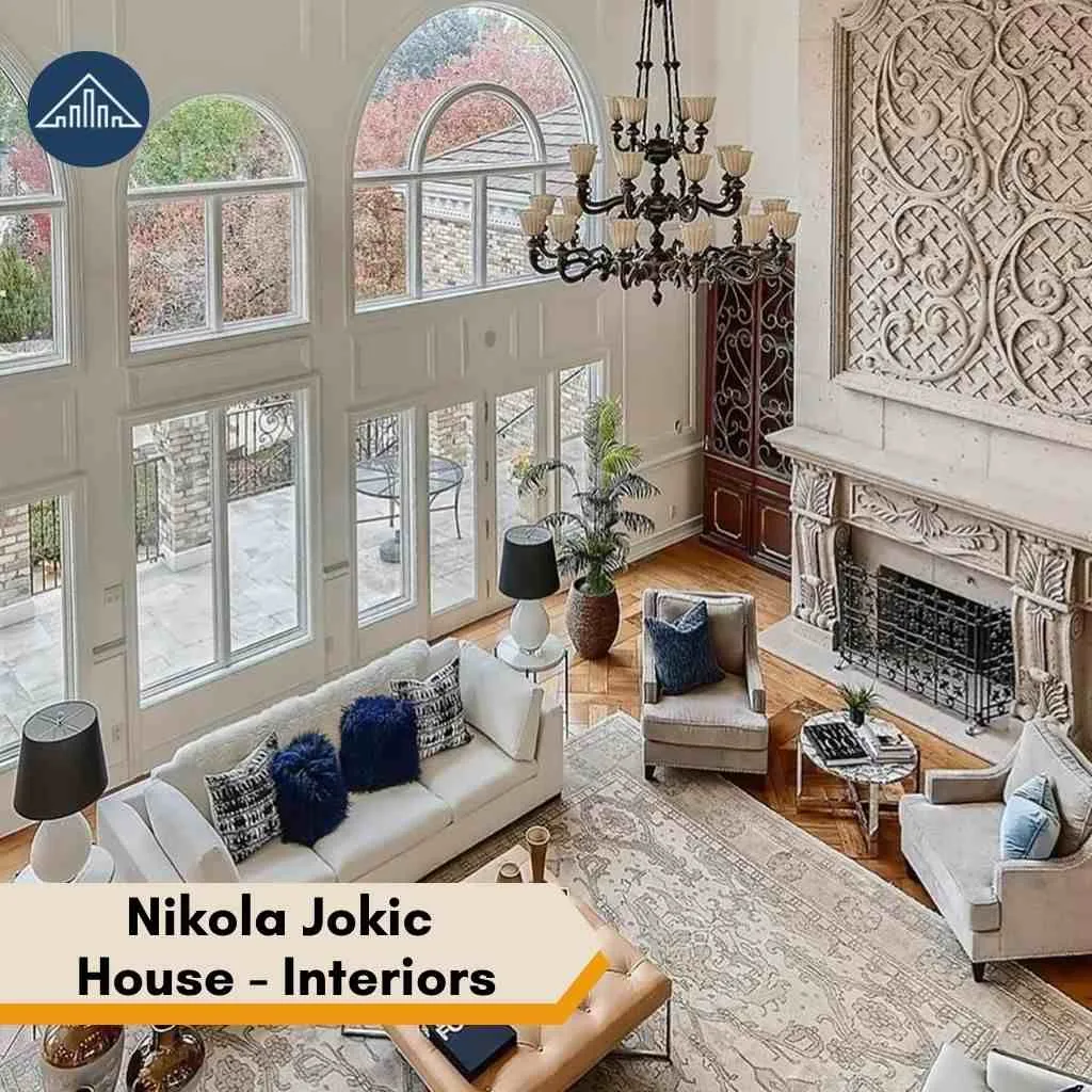 High-ceiling living room with large windows and a grand fireplace inside the Nikola Jokic house.