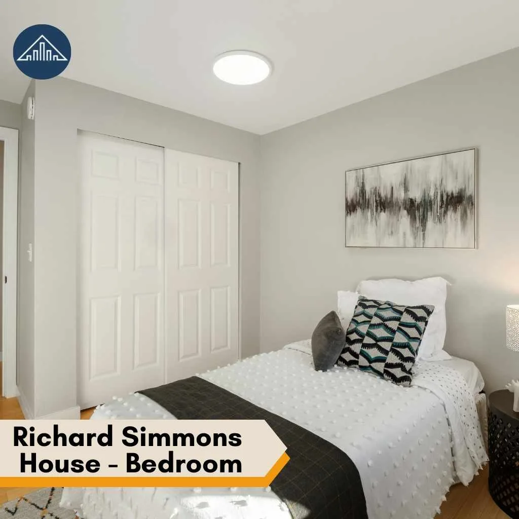 A simple bedroom inside the Richard Simmons House featuring a white bed and abstract wall art.