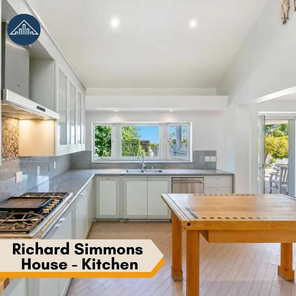 The modern kitchen inside the Richard Simmons House features white cabinetry, granite countertops, and wooden flooring.